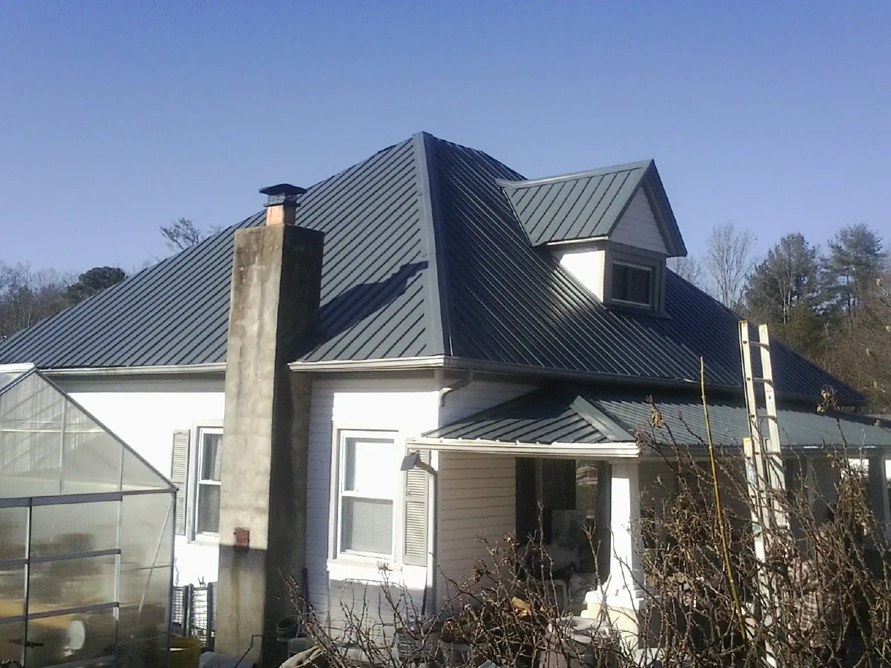 Dark blue standing seam metal roof on a white farmhouse with dormer — Slate & Tile Roof Repair by Roofing Brothers in Cookeville