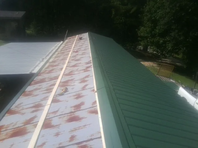 Old rusted panels beside newly installed green metal roofing — Wind Damage Roof Repair by Roofing Brothers in Cookeville