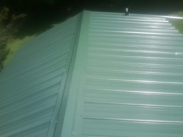 New green metal panels meeting at the ridge of a roof — Flat Roof Repair work by our crew in Cookeville