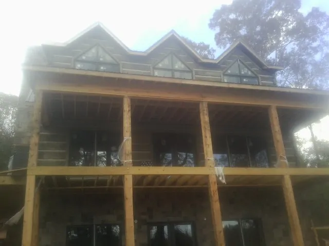 Dormers and porch framing on a large log home under construction — Roof Coating work by our crew in Cookeville