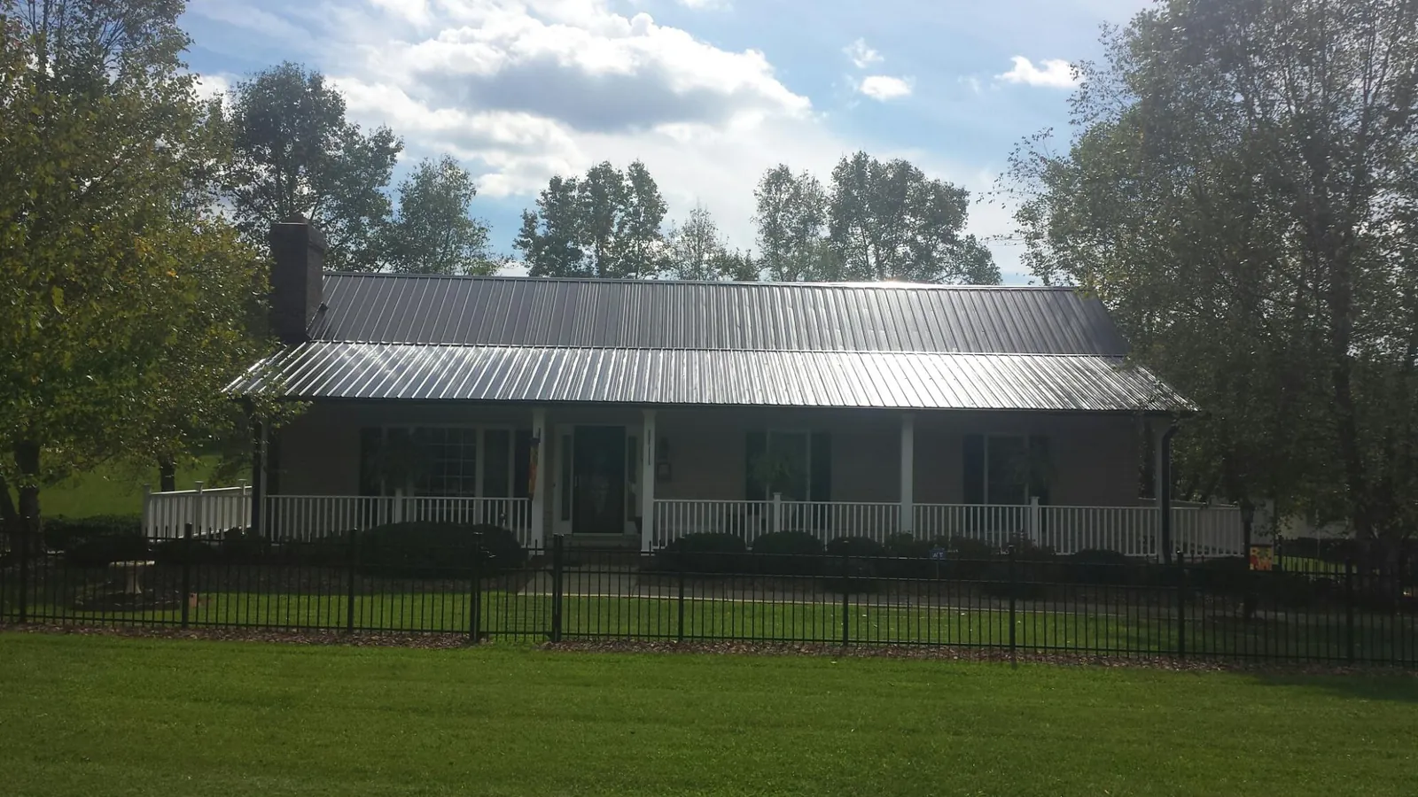 Gray metal roof on a brick ranch with a full width front porch — Gutter Guard Installation work by our crew in Cookeville