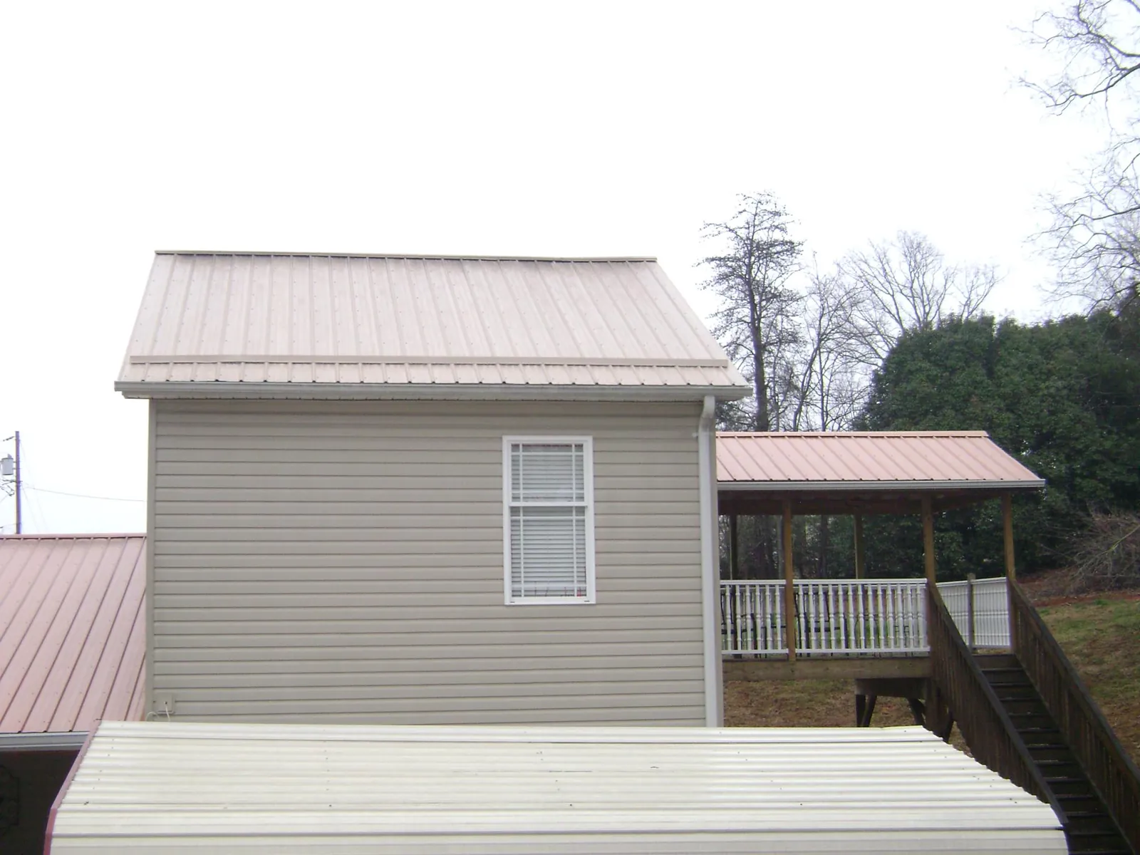 Tan metal roofs on a two story addition and attached porch, from a Roof Replacement job in Cookeville