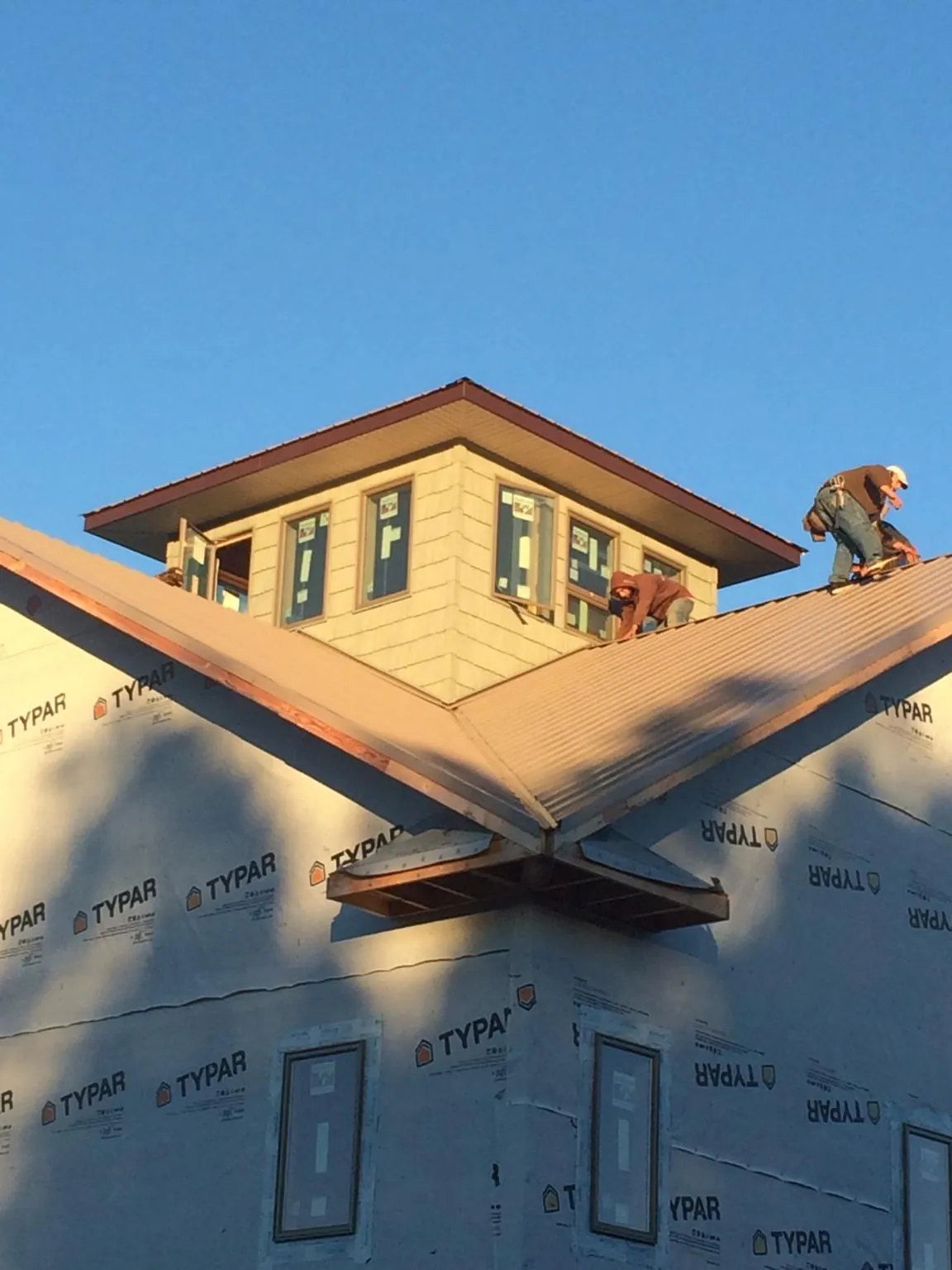 Roofers working around a rooftop cupola on a new metal roof at sunset — Roof Waterproofing in Cookeville by Roofing Brothers